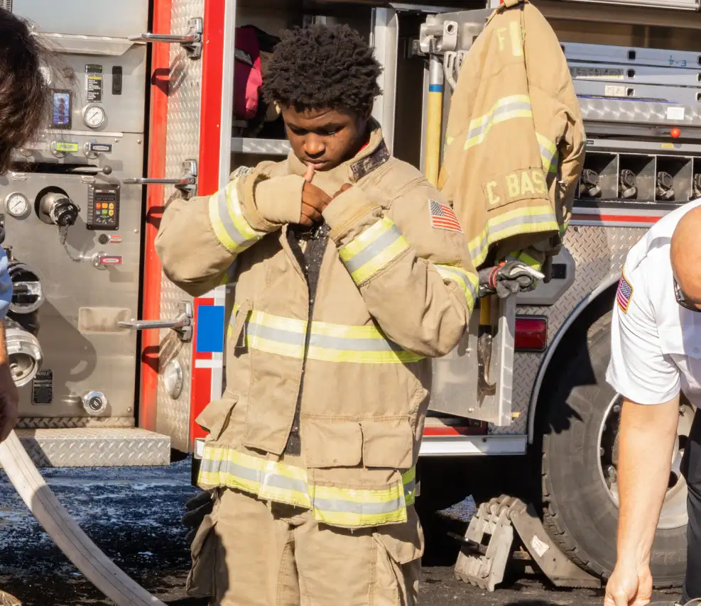 Student puts on firefighter uniform at MakerFest