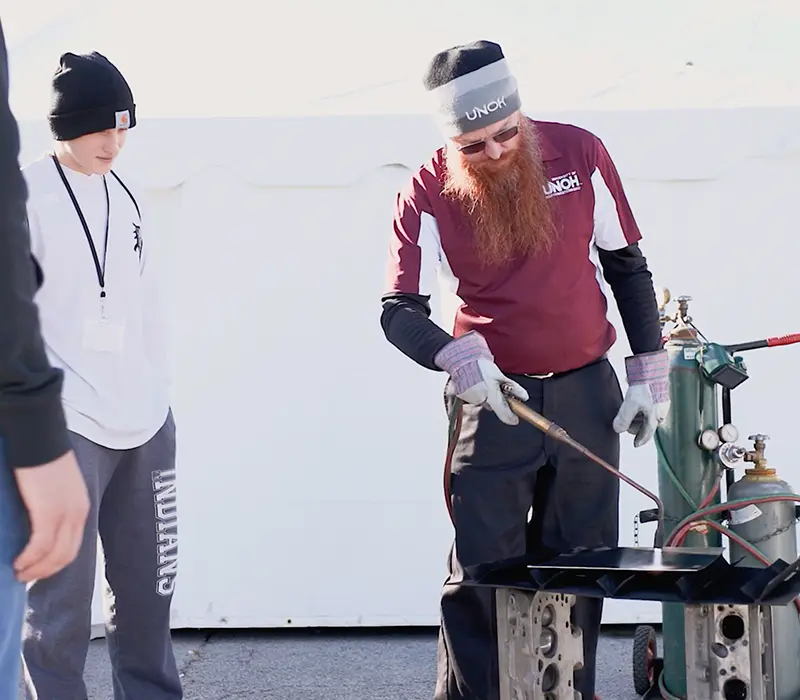 Man showing students how to use welding equipment at the MakerFest
